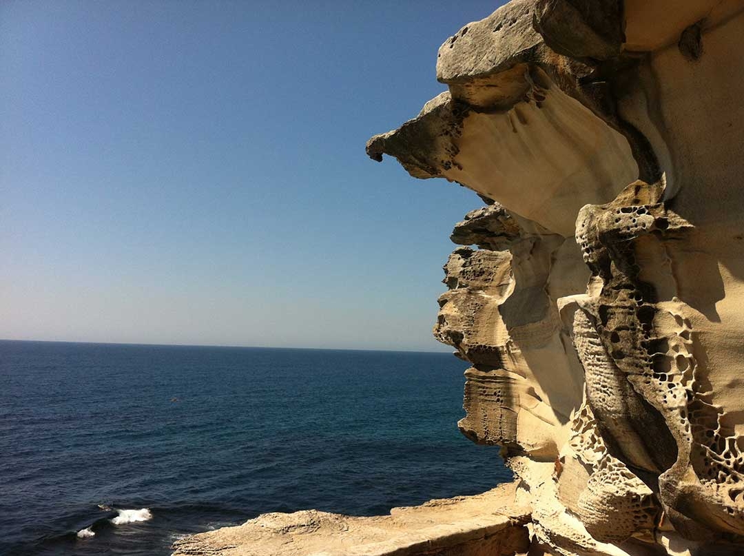 Craggy rock faces line the walk way from Bondi Beach to Bronte Beach alongside the ocean