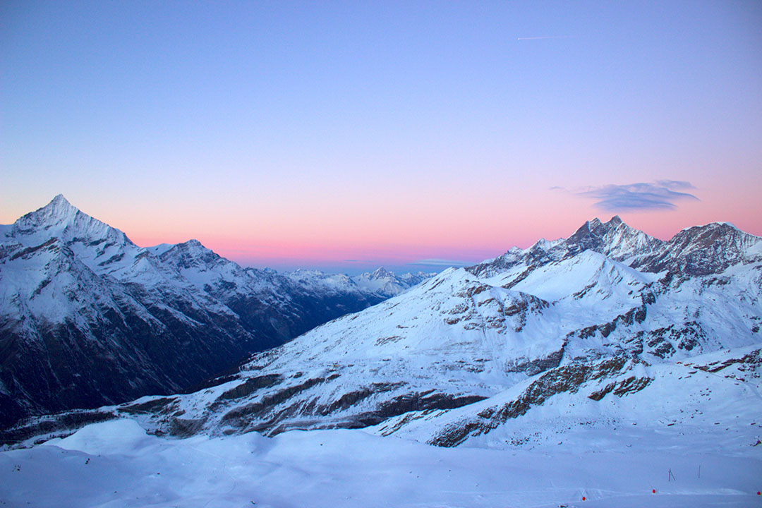 Pink sunset over the Swiss Alps covered in snow in winter in Switzerland after snow sledding