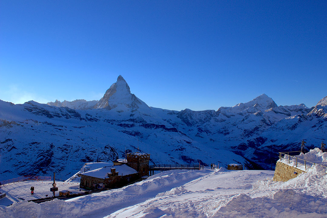 Beautiful snow covered Matterhorn in the distance against a blue winter sky while snow sledding