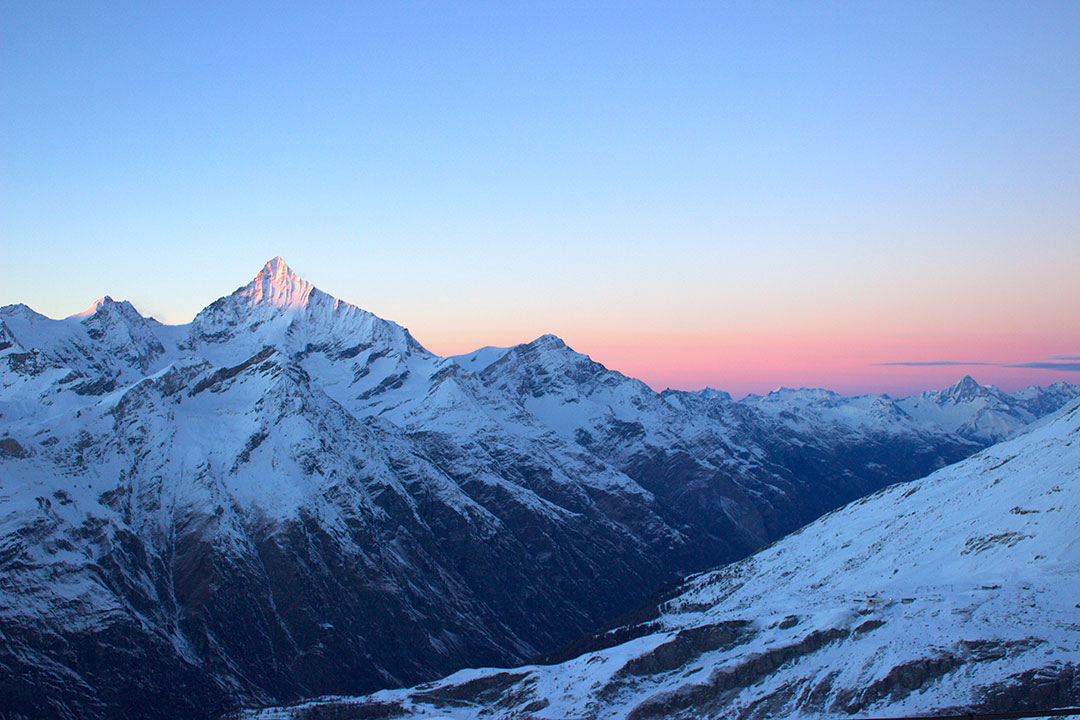 Pink sunset over the Swiss Alps covered in snow in winter in Switzerland after snow sledding