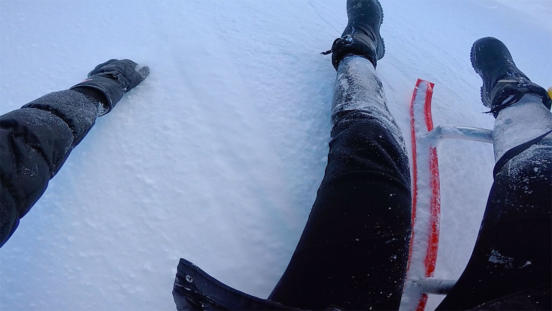 Arms and legs frantically grabbing hold of the white snow while falling of the snow sled in Switzerland in winter