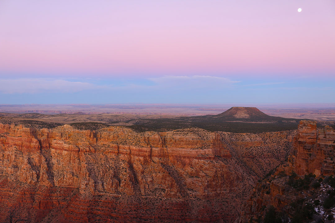 Incredible pink and blue sunset over the grand canyon with a full moon