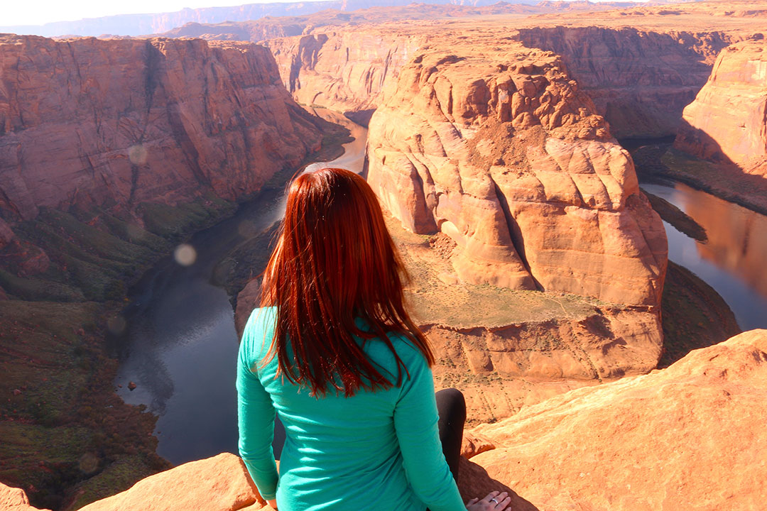 Me sitting on the cliff edge of Horse Shoe Bend overlooking the red rock and deep green water of the Colorado River