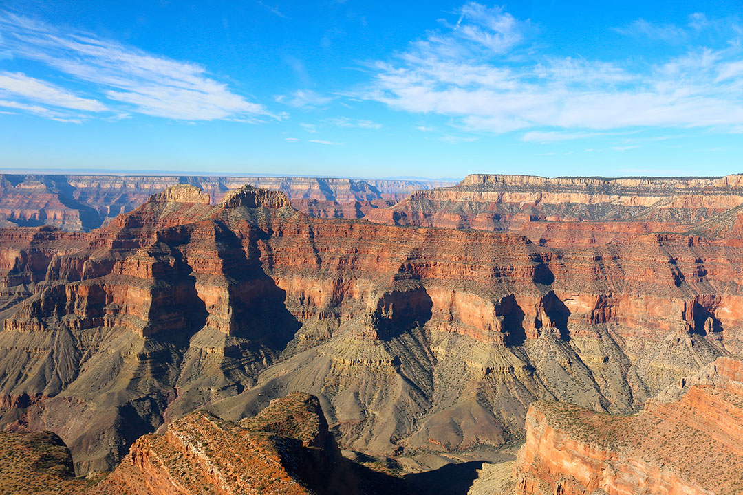 Beautiful helicopter views of the colourful red rock layers of the Grand Canyon on a brilliant blue sky day