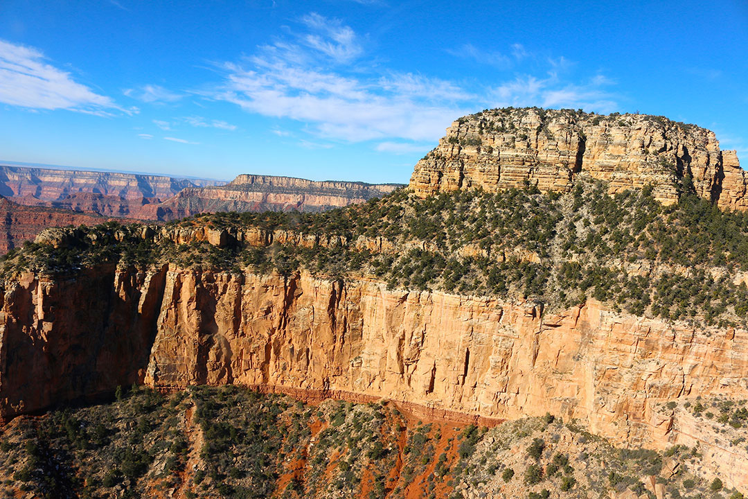 Beautiful helicopter views of the colourful red rock layers of the Grand Canyon on a brilliant blue sky day