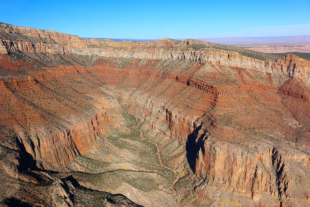 Beautiful helicopter views of the colourful red rock layers of the Grand Canyon on a brilliant blue sky day