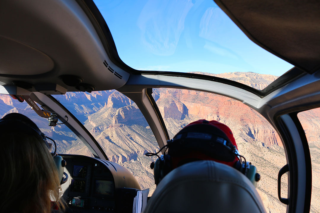 Beautiful helicopter views of the colourful red rock layers of the Grand Canyon on a brilliant blue sky day