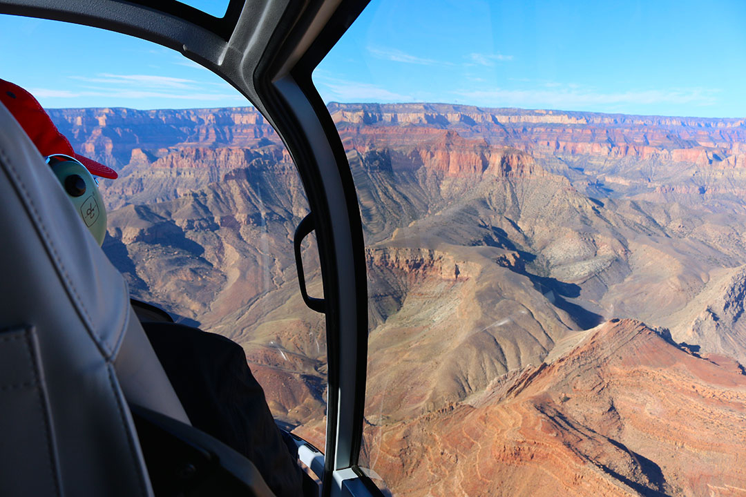 Beautiful helicopter views of the colourful red rock layers of the Grand Canyon on a brilliant blue sky day