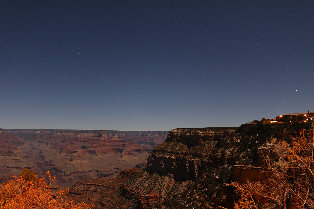 Warm red tones of the Grand Canyon at night with faint stars in the dark sky