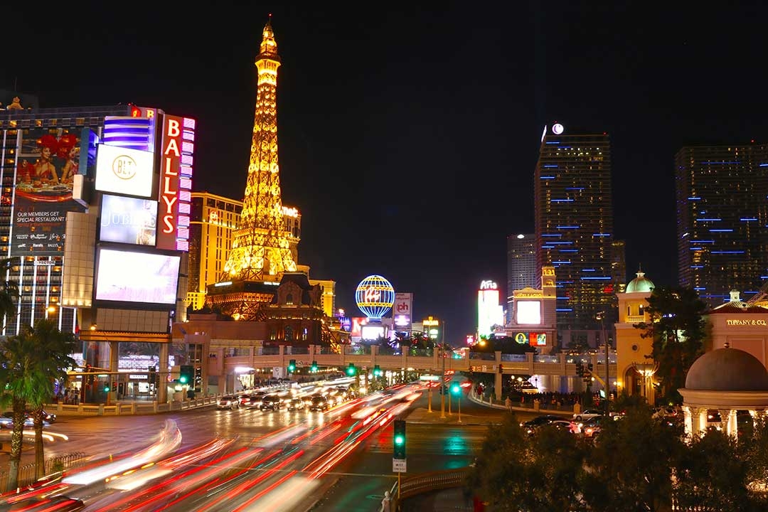 Bright lights of Las Vegas at night as the lights of cars fly by on the road