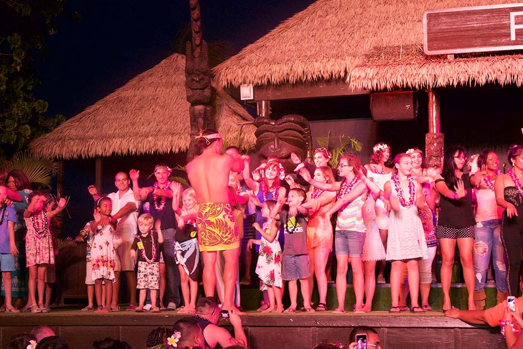 My friends and I participating in a dance on stage with other tourists at the Paradise Cove Luau