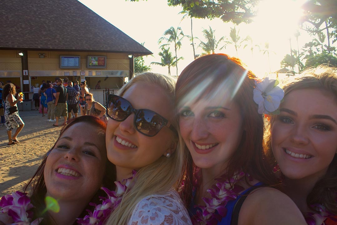 My friends and I at the Luau smiling with flowers in our hair and leis around our neck on a sunny spring day