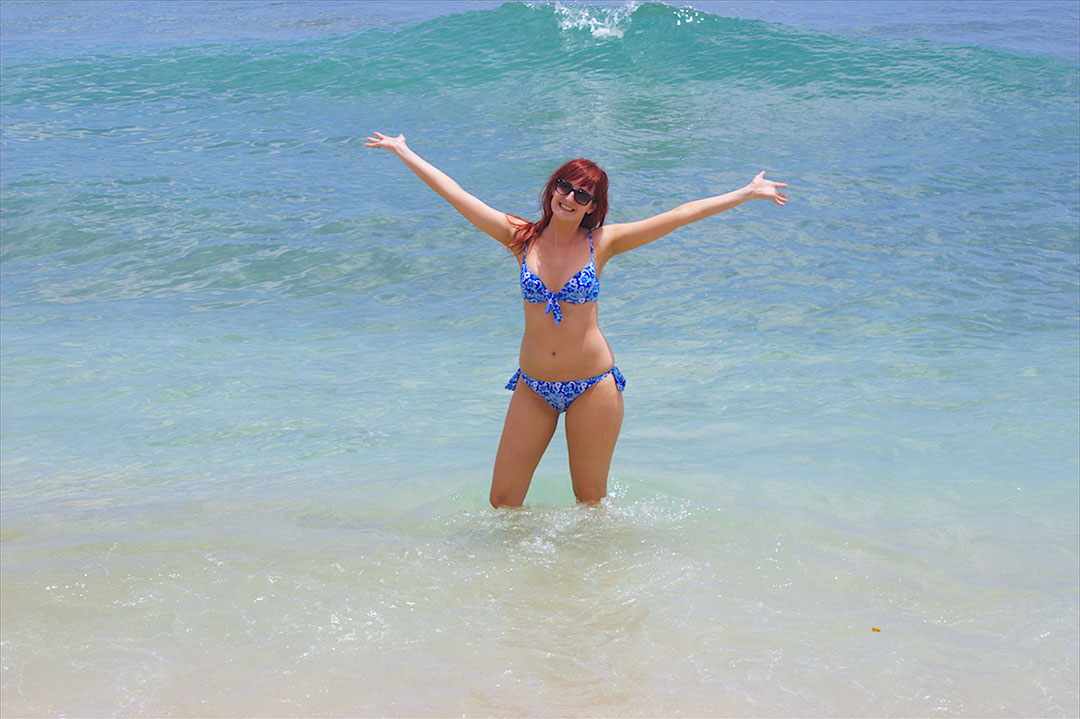 Me standing knee deep in the ocean smiling with my hands in the air