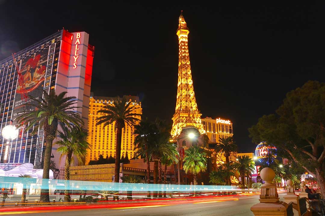 Bright lights of Las Vegas at night as the lights of cars fly by on the road