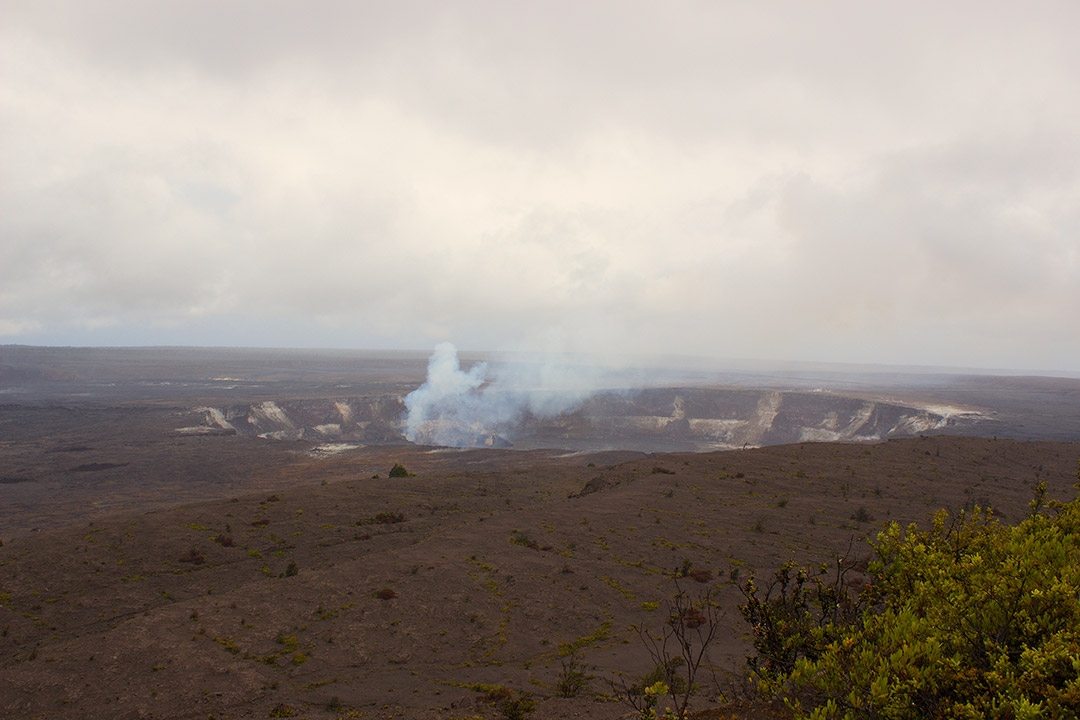 View from afar of a steaming volcano inside Hawaii Volcanoes National Park