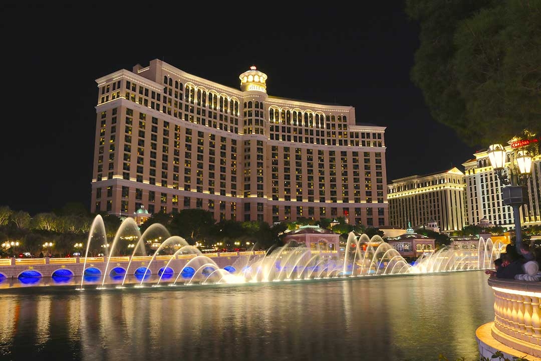 Las Vegas at night lit up with coloured buildings and giant water features