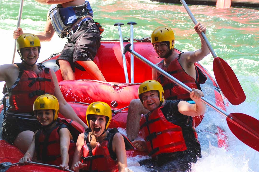 Mum and I with our white water rafting group with our oars in the air and smiling while celebrating that we conquered the highest commercially rafted waterfall in the world