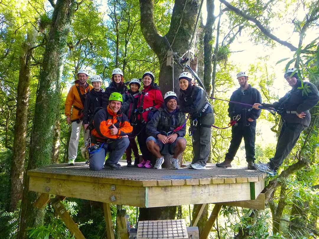 My group of zipliners standing on a high platform among the tree tops all harnessed in ready to go zip lining in Rotorua, New Zealand