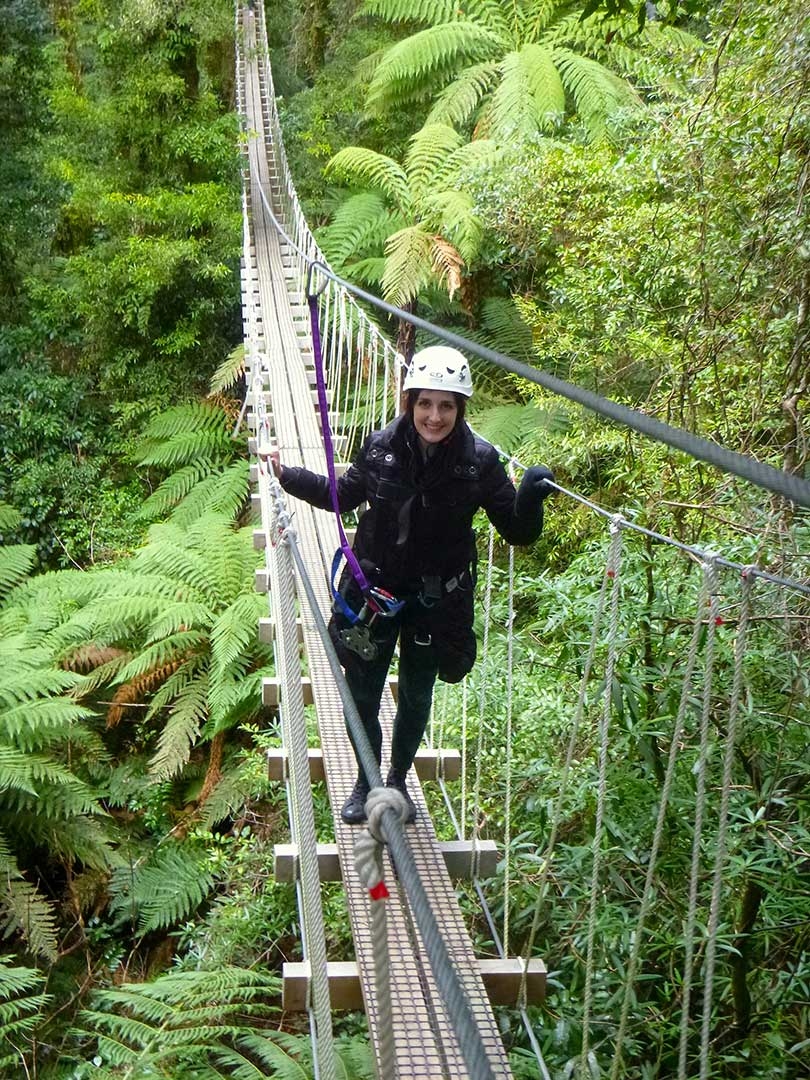 Me standing on a swing bridge smiling while walking to the next platform to go zip lining in Rotorua, New Zealand