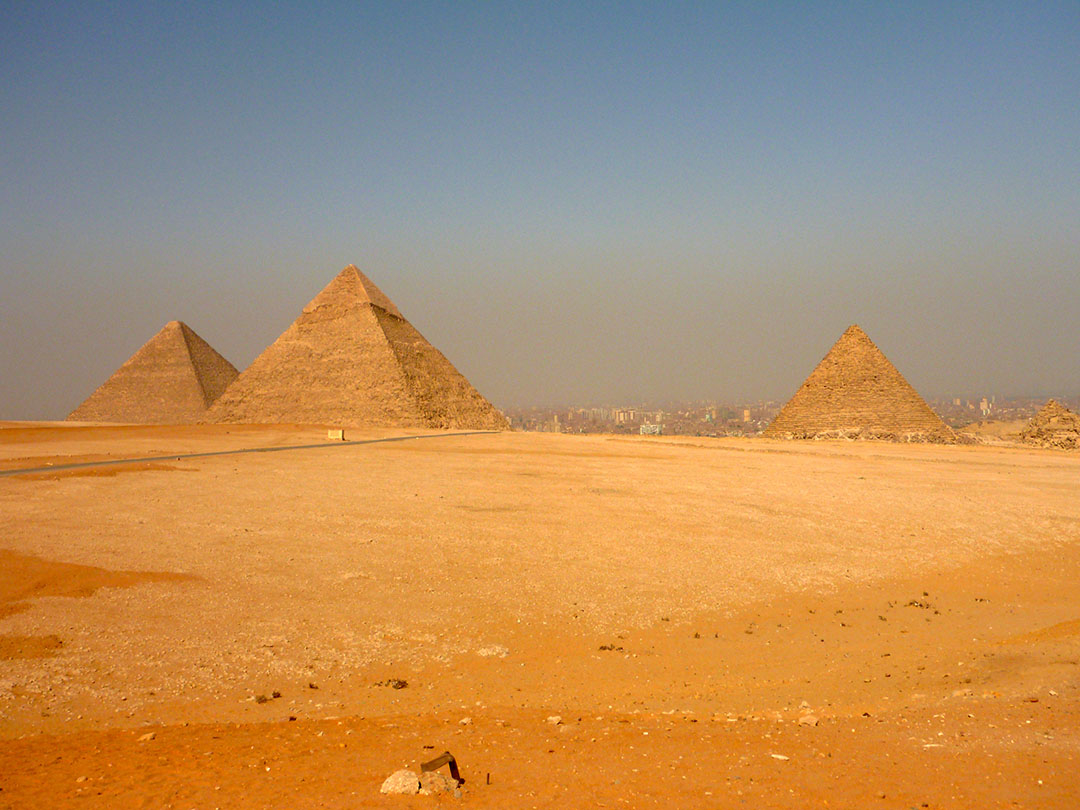 The Pyramids of Giza with the city in the background on a dusty hot summer day