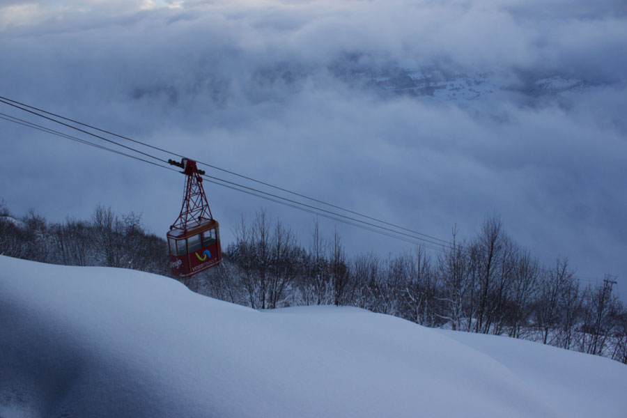 Ski lift above the clouds in Voss, Norway during winter surrounded by snow and bare trees