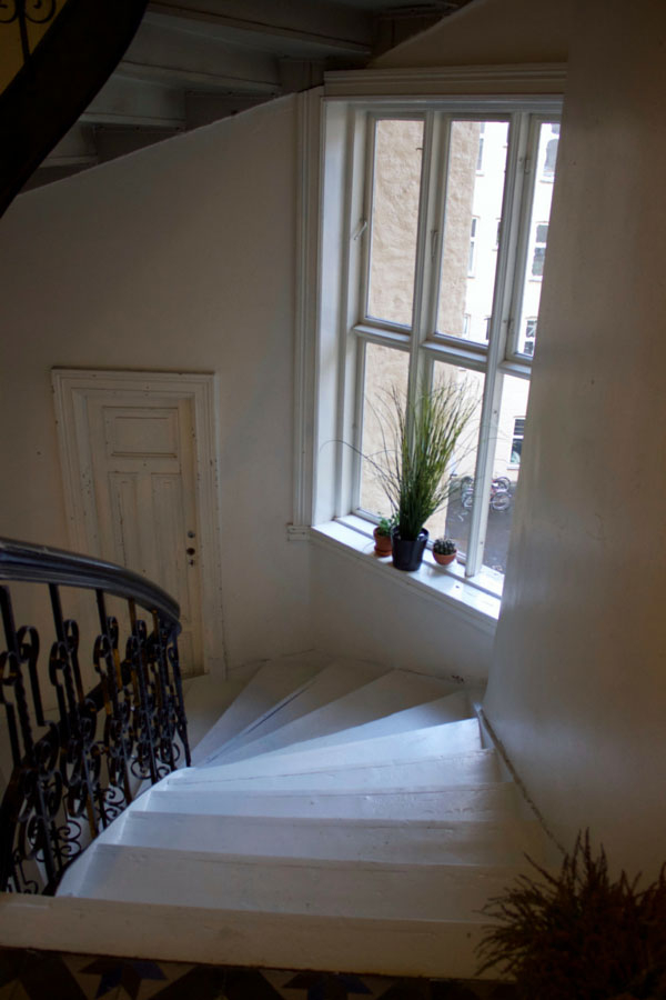 Looking down the white spiral staircase from my airbnb apartment in Oslo, Norway with a window looking out to a beautiful winter day